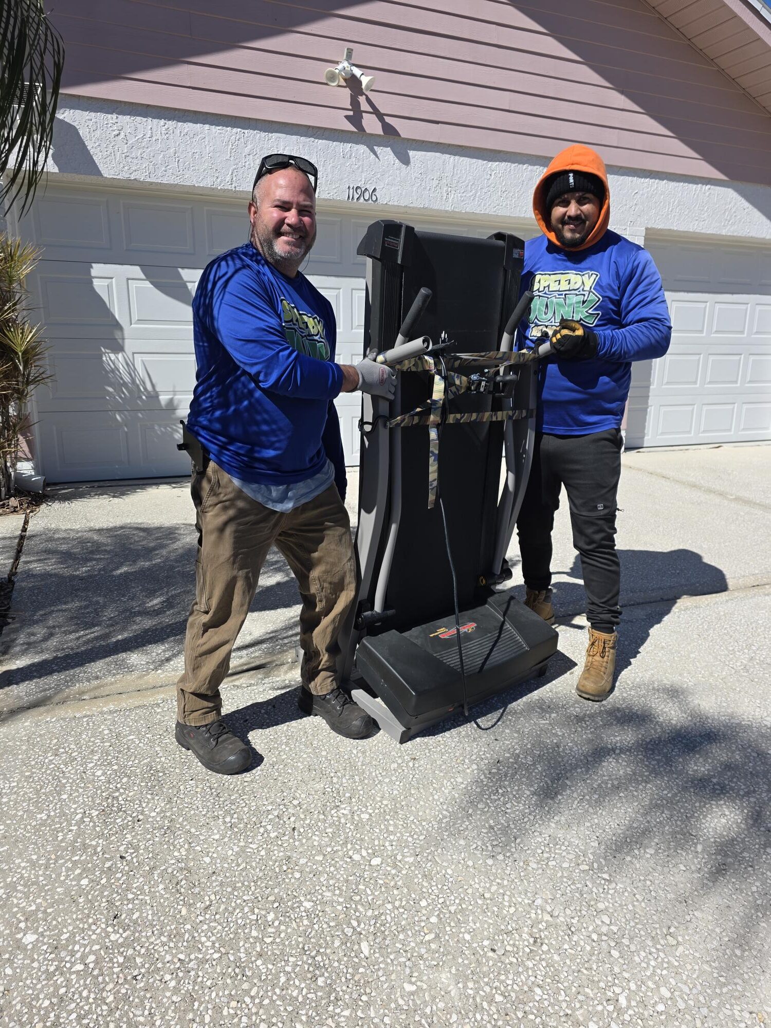 Junk removal crew holding a treadmill during a garage cleanout in Westchase Florida