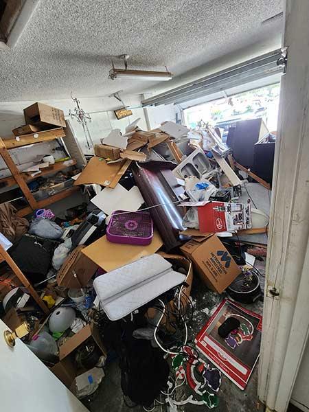 Cluttered garage with junk pile in Tampa before removal